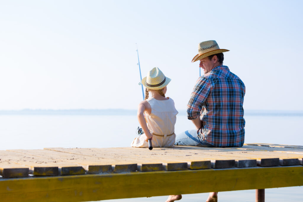 A father and daughter sitting on a dock and fishing. ID 46857000 © Nexusplexus | Dreamstime.com