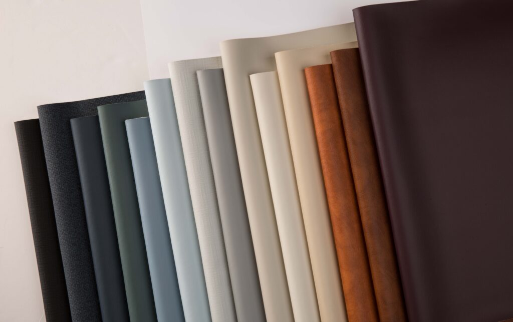 Collection of vinyl fabric swatches in various colors, including dark gray, teal, beige, brown and deep burgundy.