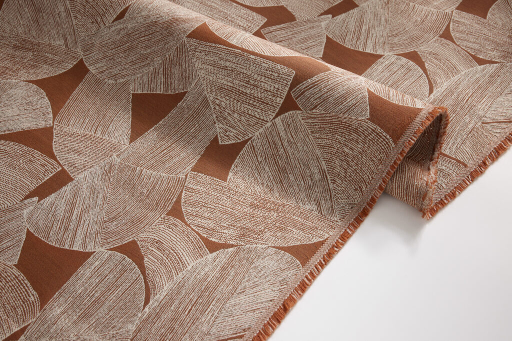 Textured fabric featuring a terracotta base with abstract, light-colored circular and leaf-like patterns.