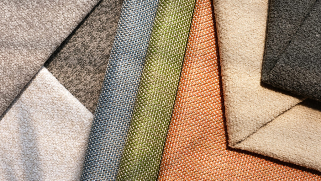 A collection of versatile outdoor fabrics in various colors, including greys, greens, oranges and beiges, layered in an overlapping arrangement.